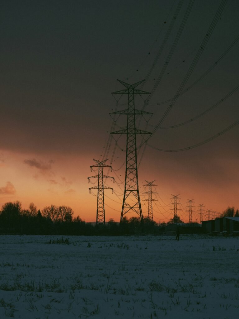 High-voltage power transmission towers forming a power grid at sunset, symbolizing electricity infrastructure and unstable power supply.