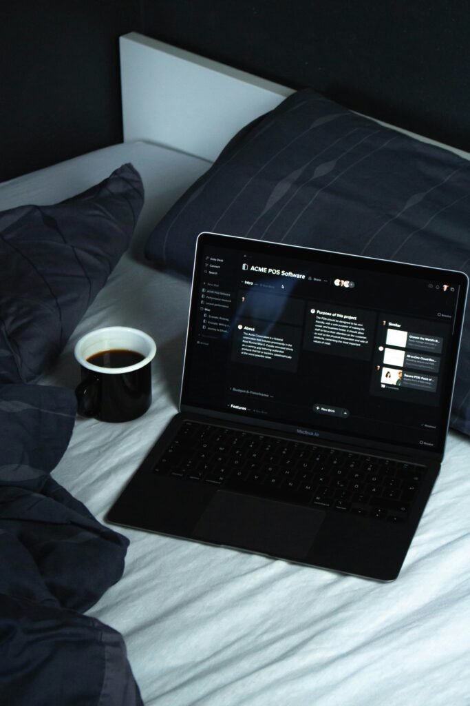 Laptop on a bed displaying work documents beside a cup of coffee, representing calm remote freelancing with AI tools.