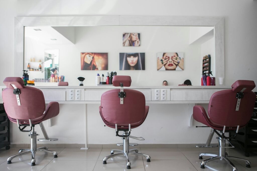 An empty salon chair facing a large mirror in a Nigerian hair salon, with natural light filtering in and styling tools neatly arranged on the counter.