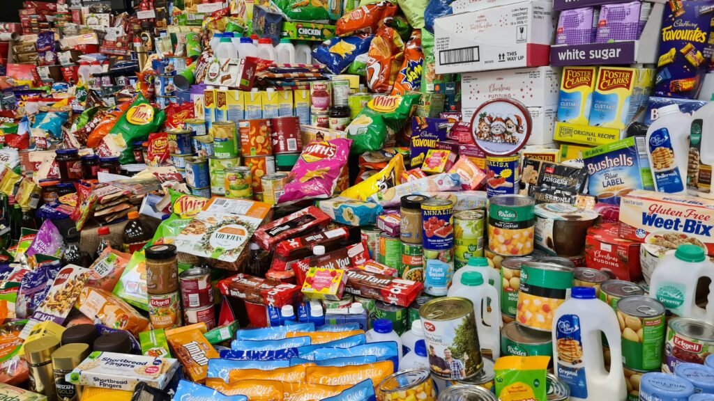 A densely stocked Nigerian provision store shelf, packed with groceries, drinks, and essentials, representing the tangible inventory of a busy business.